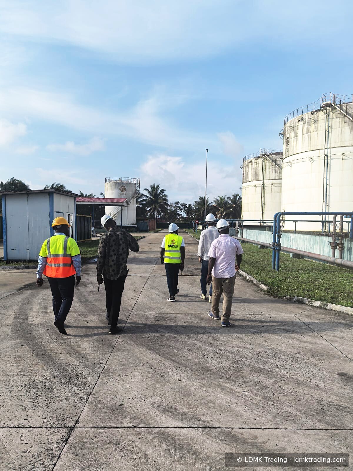 LDMK team walking toward large white storage tanks wearing high-visibility PPE.